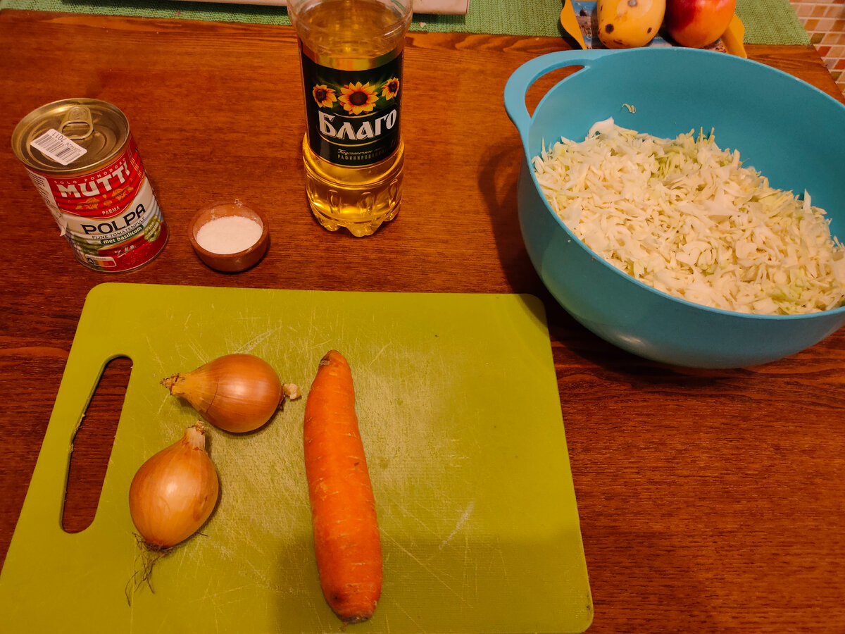 Подготавливаем все ингредиенты:
Капуста белокочанная - 700-1000 грамм, зависит от объёма вашей сковороды. 
Томаты в собственном соку (Свежие консервированные, резаные или измельчённые) — 400 г
Морковь (Средняя) — 1 шт
Лук репчатый (Средний) — 2 шт
Соль — по вкусу
Перец черный молотый, или смесь перцев — по вкусу
Масло подсолнечное для жарки — 50 мл
Овощи чистим и моем, капусту нарезаем (шинкуем). Я использовал кухонный комбайн.