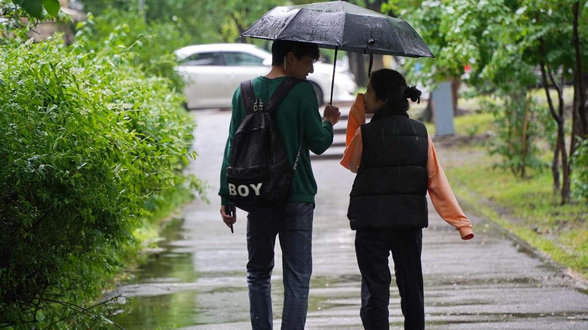    Парень и девушка идут под зонтом:NUR.KZ/Владимир Третьяков