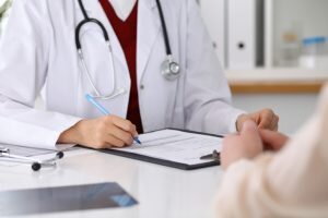    Close up of a female doctor filling up an application form while consulting patient. Medicine and health care concept Галатея Петрова