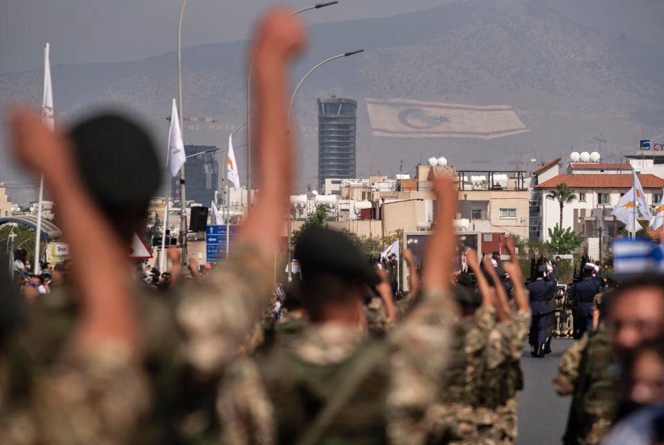 Бойцы Национальной гвардии Кипра принимают участие в военном параде, посвящ`нном 61-й годовщине независимости Республики Кипр от британского колониального господства, 1 октября 2021 года. На заднем плане виден флаг отколовшейся Турецкой Республики Северного Кипра. нарисованном на горном массиве Кирении. (Фото Яковоса Хациставру / AFP / GETTY IMAGES