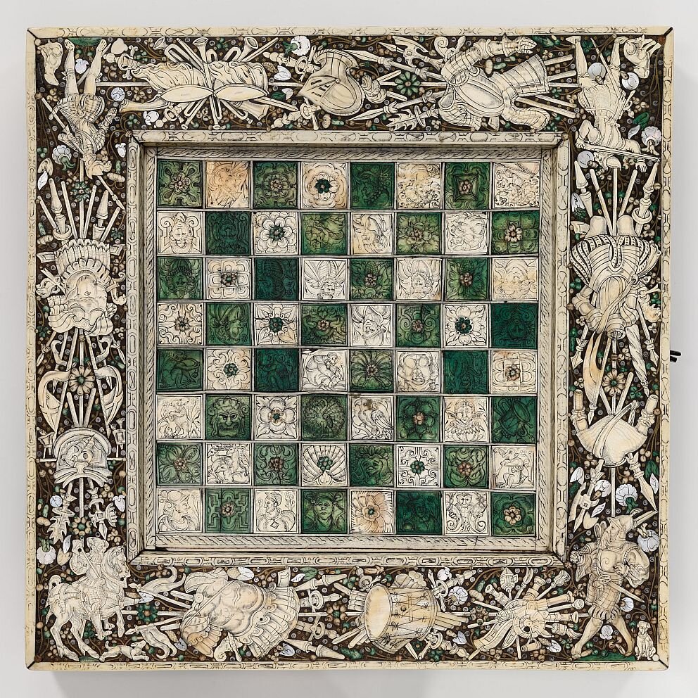 Шахматная доска. Центральная часть набрана из белых и окрашенных зеленых квадратов из слоновой кости. Каждый квадрат украшен гравировкой, мотив которой не повторяется ни в одной клетке. 