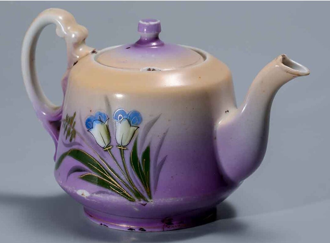 Чайник заварной фарфоровый, в верхней части бежевый, снизу сиреневый с рисунком Колокольчики. На дне клеймо: Н.Т.Ф. Бронницы. кон. XIX - нач. XX века.Период создания:XIX. Местонахождение. Муниципальное автономное учреждение культуры Орский краеведческий музей. Госкаталог.РФ.