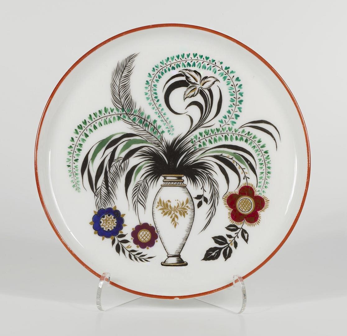 Поднос с изображением вазы со стилизованными цветами и листьями. 1920. Этот поднос также присутствовал в статье о С.В. Чехонине. И вот почему: автор композиции Чехонин С.В., исполнитель Рукавишникова В.Ф. Роспись надглазурная полихромная. Размеры: 1,3*16,7 см. Собрание Эрмитажа. Предмет поступил в 2002-м году. Передан в составе коллекции Музея Фарфорового завода. Инв. номер Мз-С-3159. Изображение взято из каталога Эрмитажа.