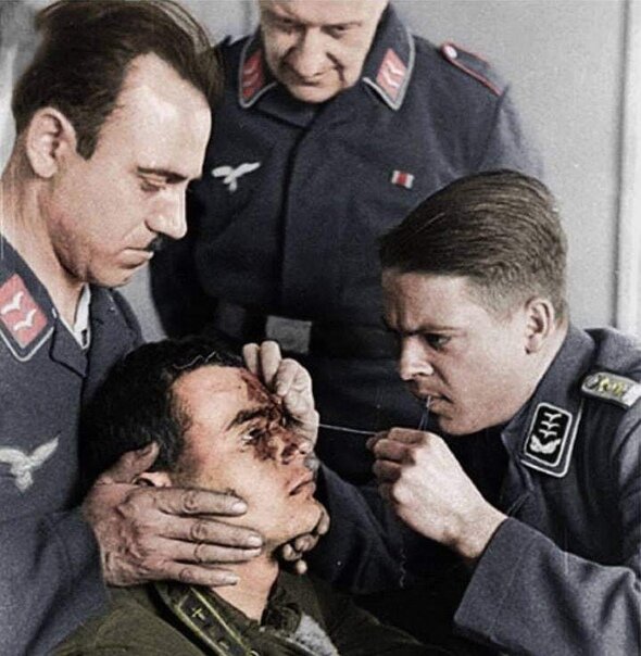 Немецкие лётчики зашивают рану пленному советскому лётчику, 1941 год