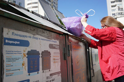    Женщина выбрасывает мешок с мусором в контейнер для раздельных отходов ©Пелагия Тихонова РИАМО