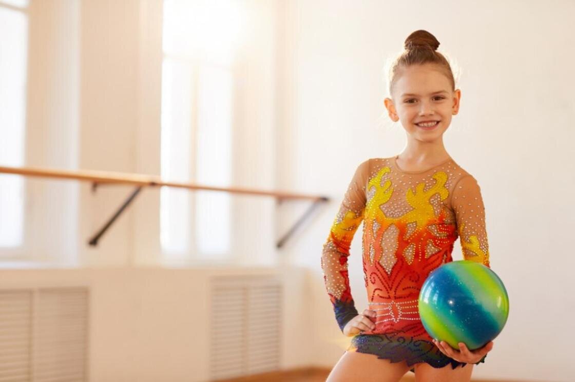    Девочка в гимнастическом трико с мячом:Freepik