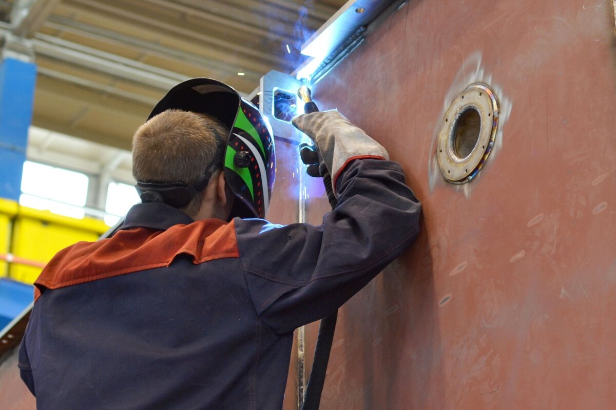 сварщик на заводе. сварочные работы. сварка металлоконструкций. электросварщик ручной сварки. сварщик ручной дуговой сварки плавящимся покрытым электродом.