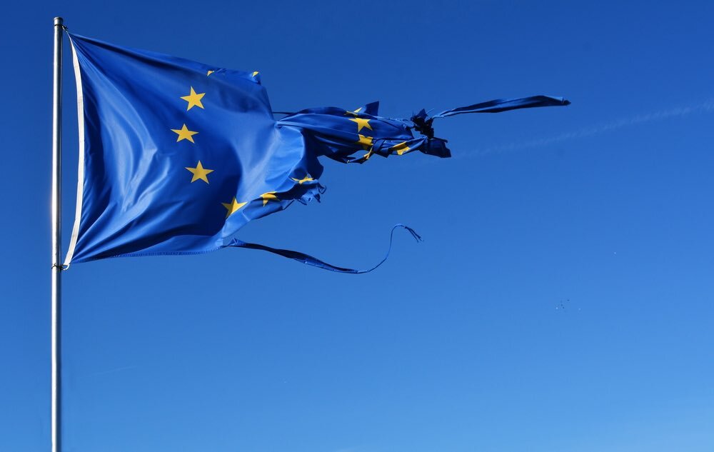    The european union twelve star flag torn and with knots in the wind on blue sky pipiya