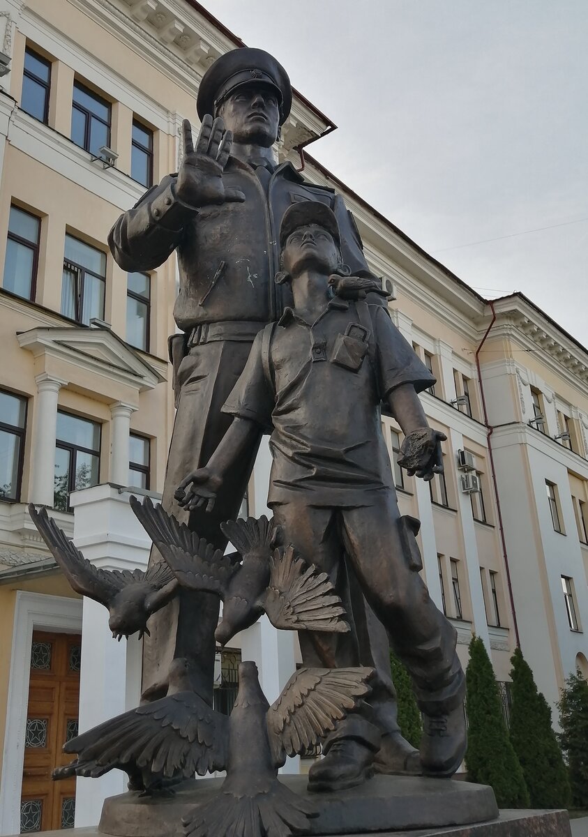 Изображён мальчик с краюхой хлеба, кормящий тверских голубей, покой и безопасность которого охраняет доблестный страж порядка.