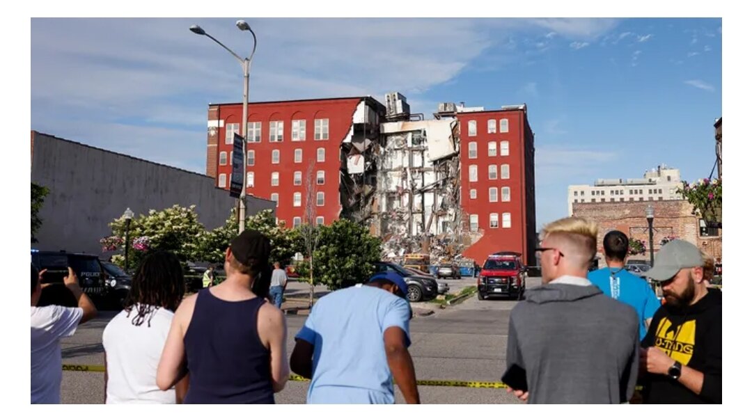 Зрители наблюдают, как бригады скорой помощи работают на месте частичного обрушения здания в 300-м квартале Мейн-стрит в Давенпорте, штат Айова.  (Никос Фрейзер/Quad City Times через AP)