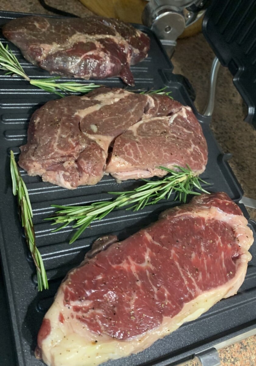 1)Достанем мясо заранее из холодильника, освободим от упаковки, чтобы оно полежало минут 20 при комнатной температуре. Это необходимо, чтобы при обжаривании на гриле выделилось меньше сока и стейк получился сочнее. Промокните  бумажными полотенцами.
2)Мариновать стейки для приготовления на гриле не нужно. Достаточно натереть солью и перцем, затем смазать растительным маслом по желаю при жарке можно добавить веточки тимьяна.  3)Разогреваем гриль с установленными рифлеными пластинами до максимальной температуры. Нам важно, чтобы мясо сразу же «запечаталось» корочкой и сохранило свою сочность. На моем гриле Delonghi для мяса есть режим SEAR — это максимальный прогрев. Температуру выставляем 230˚C.
4)Когда электрогриль полностью разогреется, кладем стейки. 5)Закрываем гриль крышкой — стейки готовят контактным способом, то есть верхняя крышка гриля придавливает мясо. 
6)Если на гриле есть таймер, поставьте его на 7 минут. За это время 500 г стейков из говядины толщиной 1,5-2 см прожарятся до степени well done, то есть без крови. У меня стейк рибай, он довольно жирный и сочный, поэтому для него лучше делать хорошую прожарку. 7)Снимаем стейки с гриля с помощью специальной лопатки, чтобы не повредить тефлоновое покрытие пластин. Кладем мясо на лист фольги. 
8)Заворачиваем стейки в фользу и даем отдохнуть  минут 15, чтобы соки равномерно распределились. Обычно я накрываю стейки полотенцем, чтобы не остывали. 9)Дело сделано, можно подавать на стол. Следуйте рецепту, и у вас получится идеальный стейк из говядины. Подавайте его с легким овощным салатом, молодой картошкой, красным или белым соусом. Приятного аппетита!