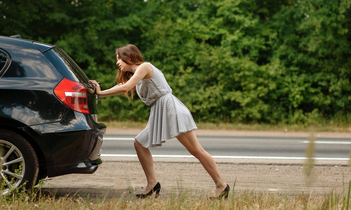 Женщина толкает автомобиль