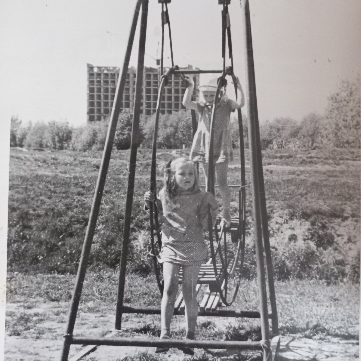 1971 год. Ленинград. Мы с подругой Верой на качелях (я стою в панамке). А  на заднем плане за проспектом Стачек строятся первые два корпуса общежитий Кораблестроительного института ("Корабелки"). Наш дом стоял на отшибе - красота!