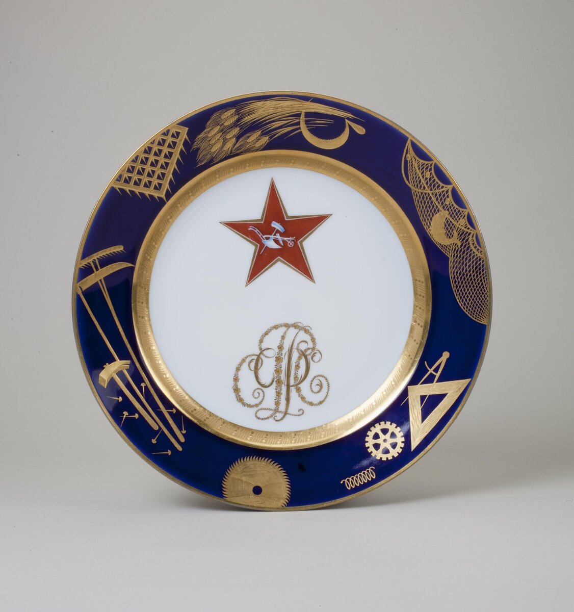 Тарелка с красной звездой и монограммой "РСФСР". ГФЗ, 1924. Автор росписи Адамович М.М. Крытье пдглазурное монохромное, роспись надглазурная полихромная, позолота, цировка. Размеры: 4,0*25,0 см. Собрание Эрмитажа. Предмет поступил в 2002-м году. Передан в составе коллекции Музея Фарфорового завода. Инв. номер Мз-С-228. Изображение взято из каталога Эрмитажа.
