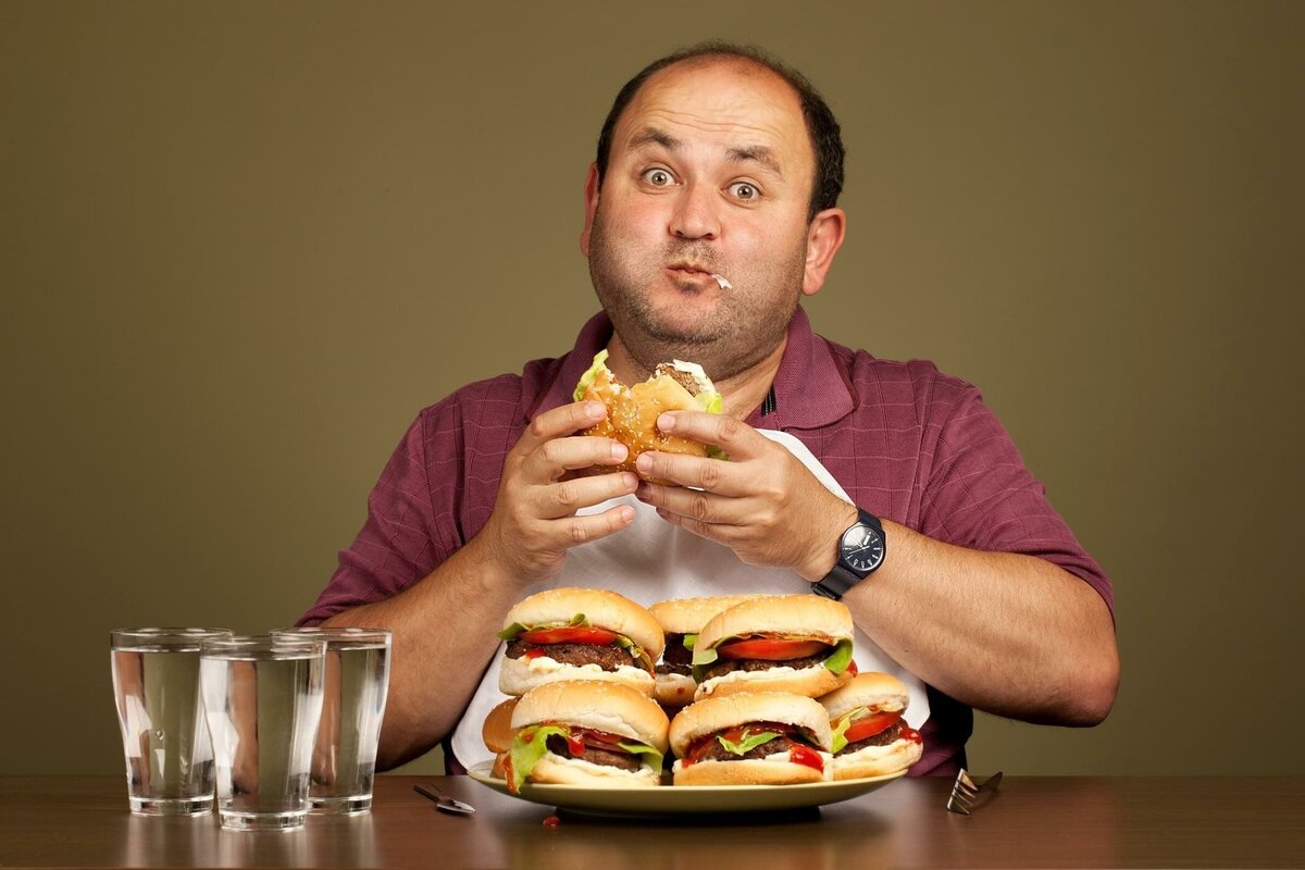 Диета для мужчин после 60 лет. Переедание. Человек ест гамбургер. Человек с едой. Мужчина и много еды.