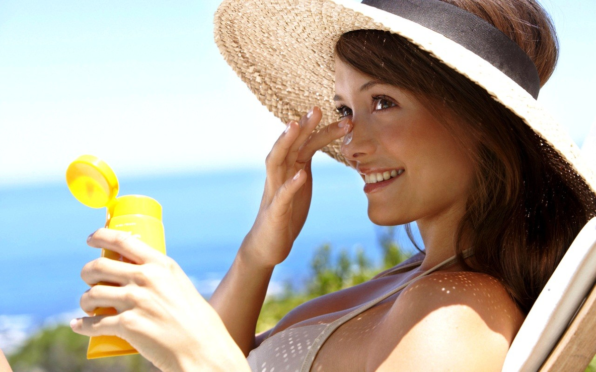 Солнцезащитный крем на пляже. Девушка в летней шляпе. Девушка в шляпе на море. Женщина солнце.
