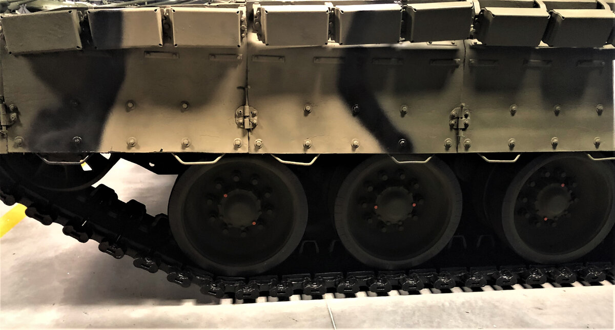 На бортах корпуса контейнеры с элементами ДЗ размещены в один ряд и перекрывают только зону размещения передних ящиков ЗИП и топливных баков на надгусеничных полках. Бортовые резинотканевые экраны усилены стальными бронепластинами, закрепленными с тыльной стороны. Такое решение применялось только на танках семейства Т-80. На танках Т-64и Т-72 бортовые экраны в зонах обитаемых отделений практически полностью перекрывались контейнерами ДЗ. 