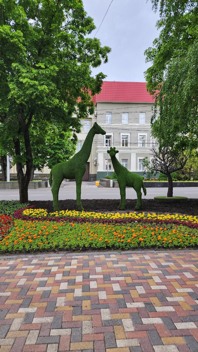 в городе везде цветы и зелёные скульптуры