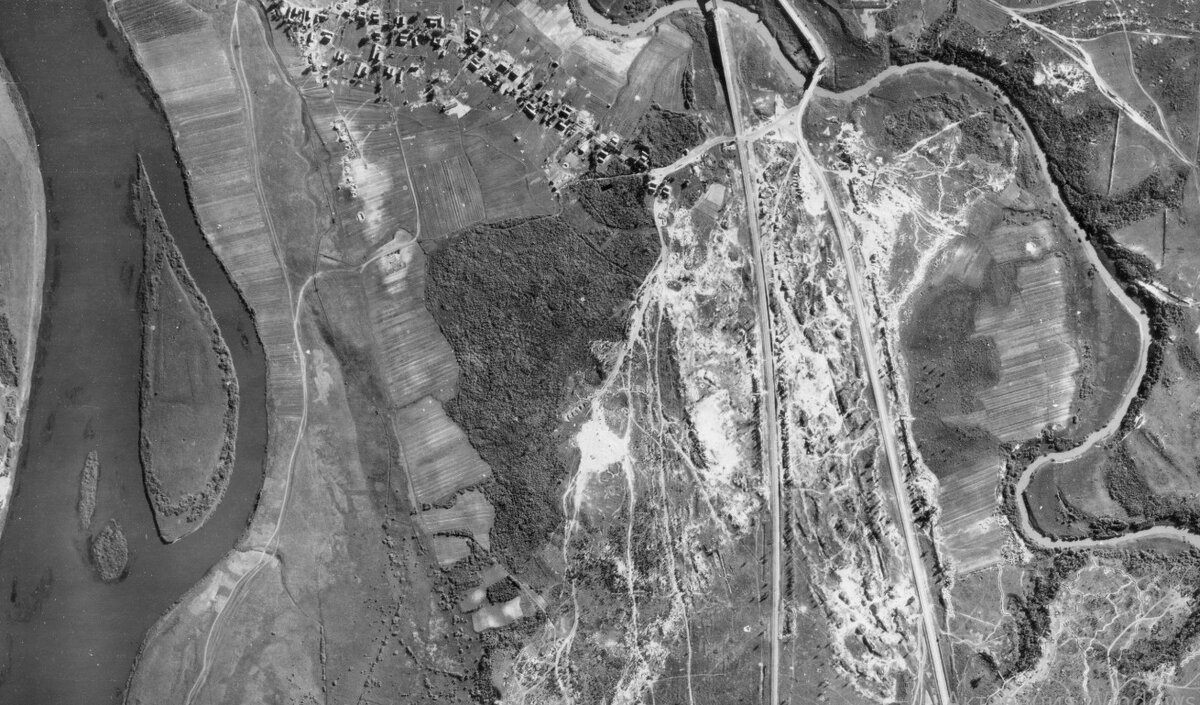 Немецкая АФС 26.06.1944. В верхней части деревня Глоты. Слева река Великая, справа Черёха. В центре сосновый лес и редколесье среди песчаных дюн. Густая сеть дорог, тропинок и землянок. Установить захоронение  1942 по снимку было практически невозможно. Две линии через снимок - шоссе и жд. на Остров. 