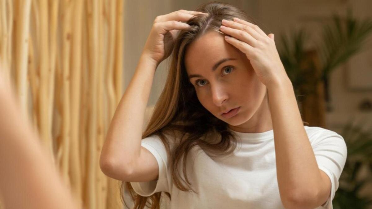    Девушка рассматривает свои волосы в зеркале:Freepik