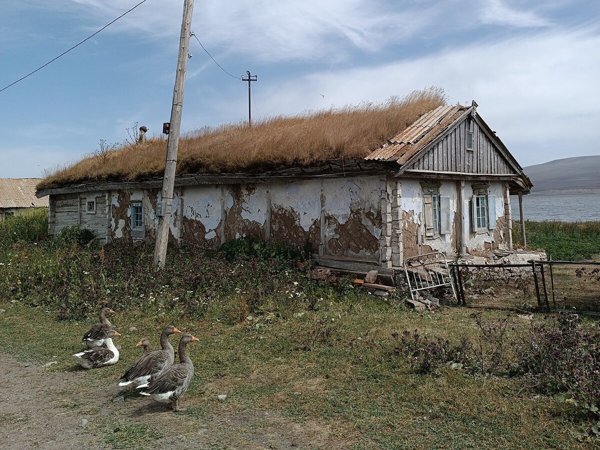 Традиционная хата духоборов в деревне Тамбовка с наличниками, ставнями и дерновой кровлей
