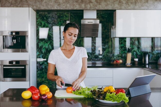 Фото с https://ru.freepik.com/premium-photo/the-young-woman-cuts-vegetables-in-the-kitchen-with-a-knife-and-laptop-on-the-table_15803502.htm