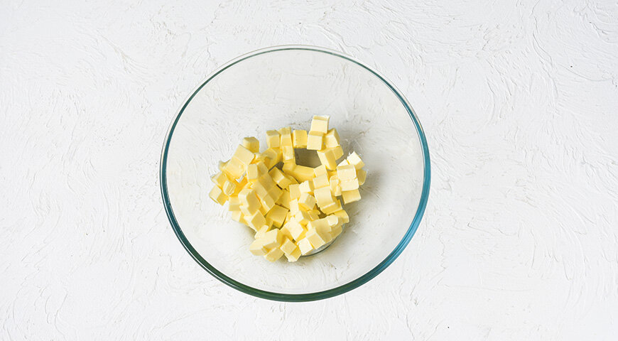 1. Подготовьте ингредиенты для теста кекса. Сливочное масло нарежьте маленькими кубиками, сложите в миску и оставьте на 30 минут при комнатной температуре, чтобы оно стало мягким.