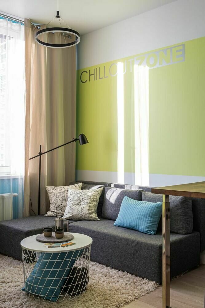 Простой серый диван дополнили металлическим коробом со столешницей, который одновременно служит журнальным столиком и местом для хранения, а также графичным торшером. Листайте галерею