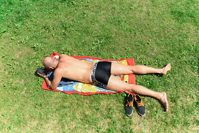    Мужчина с мобильным телефоном загорает на траве ©Пелагия Тихонова РИАМО