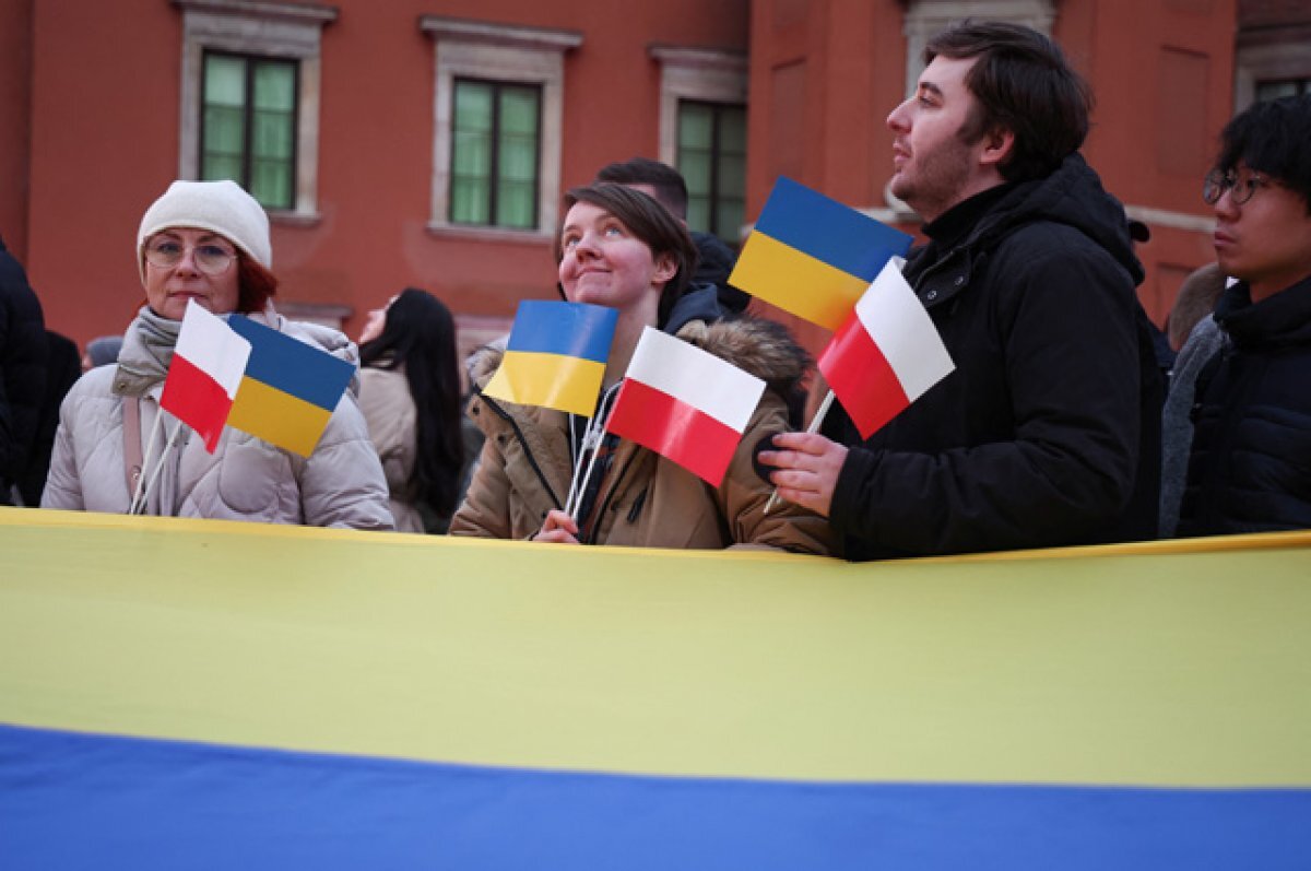    Люди держат польский и украинский флаги во дворе Королевского замка во время визита президента Украины Владимира Зеленского в Варшаву.