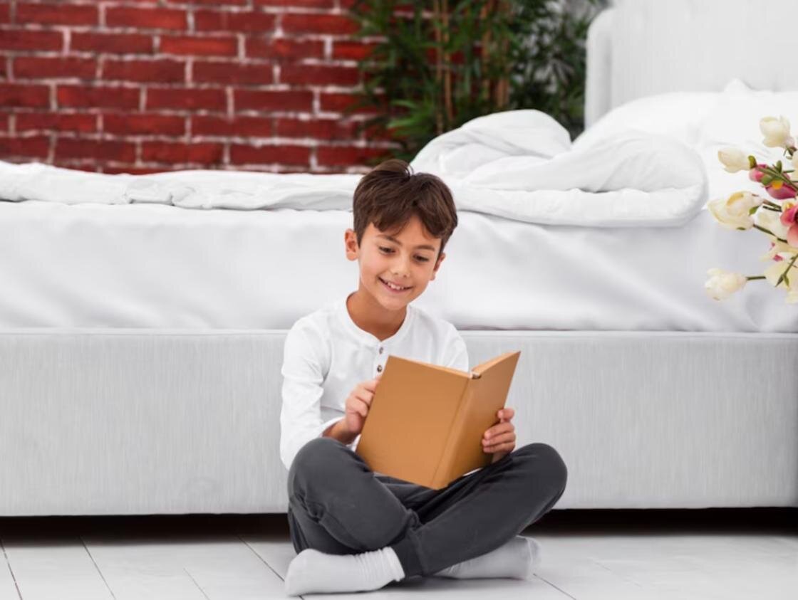    Мальчик читает книгу и улыбается:Freepik