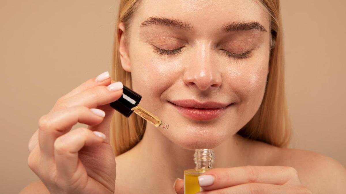    Девушка с белокурыми волосами держит в рруках бутылочку с натуральным маслом:Freepik