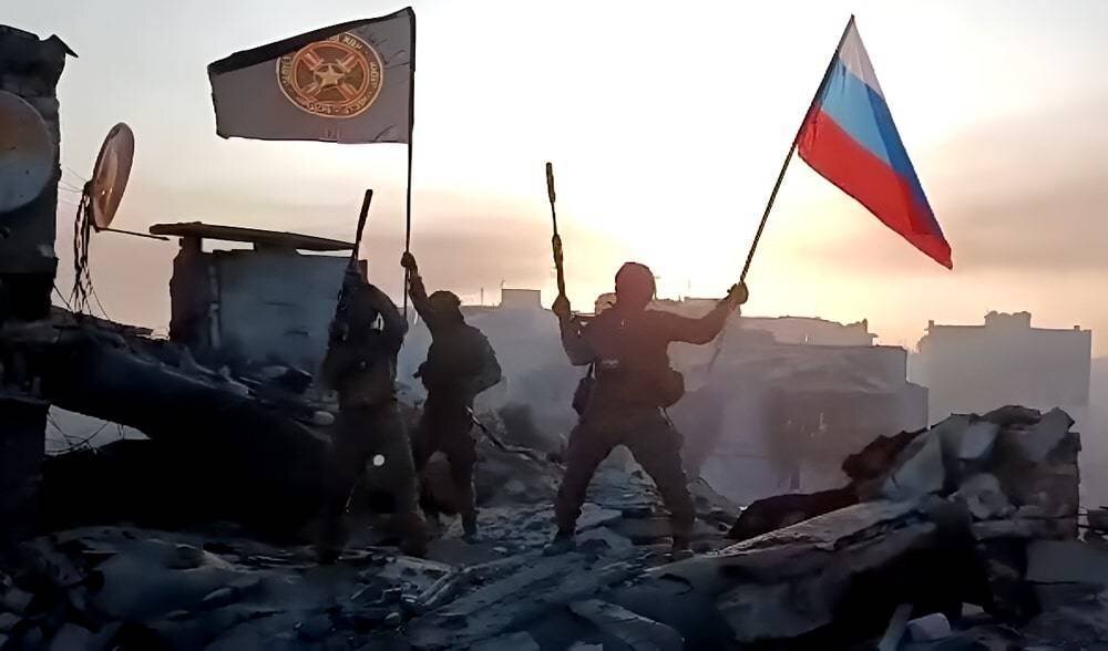 Бойцы ЧВК "Вагнер" с флагами компании и России. Фото после установления контроля над городом в результате победы над ВСУ.