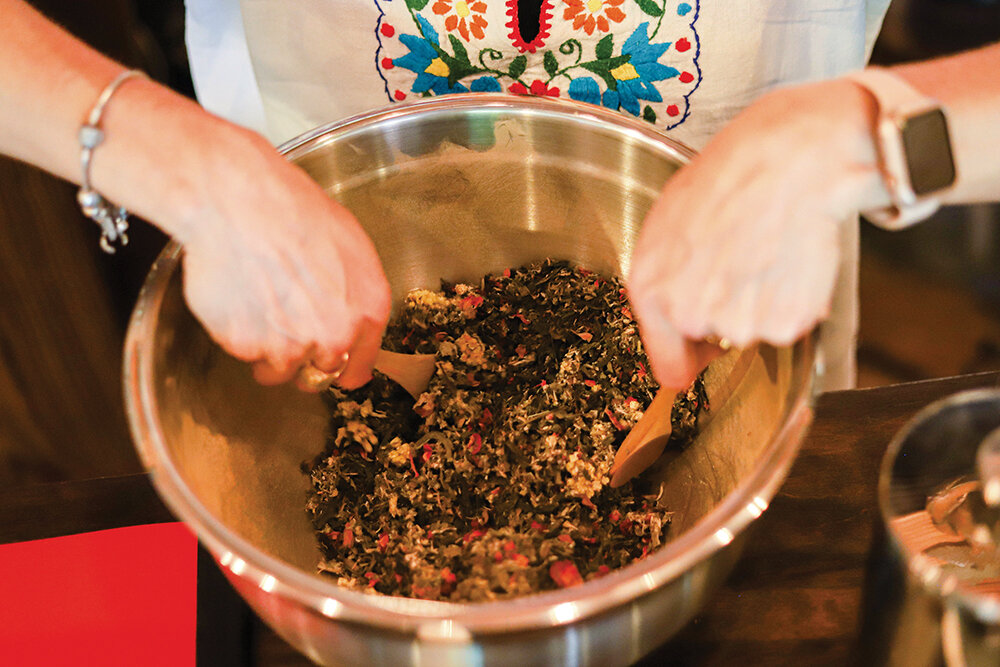 Staff photo by Olivia Ross / Rachele Marsh, owner of River of Light Studio, mixes together a custom tea blend on Friday, April 21, 2023.