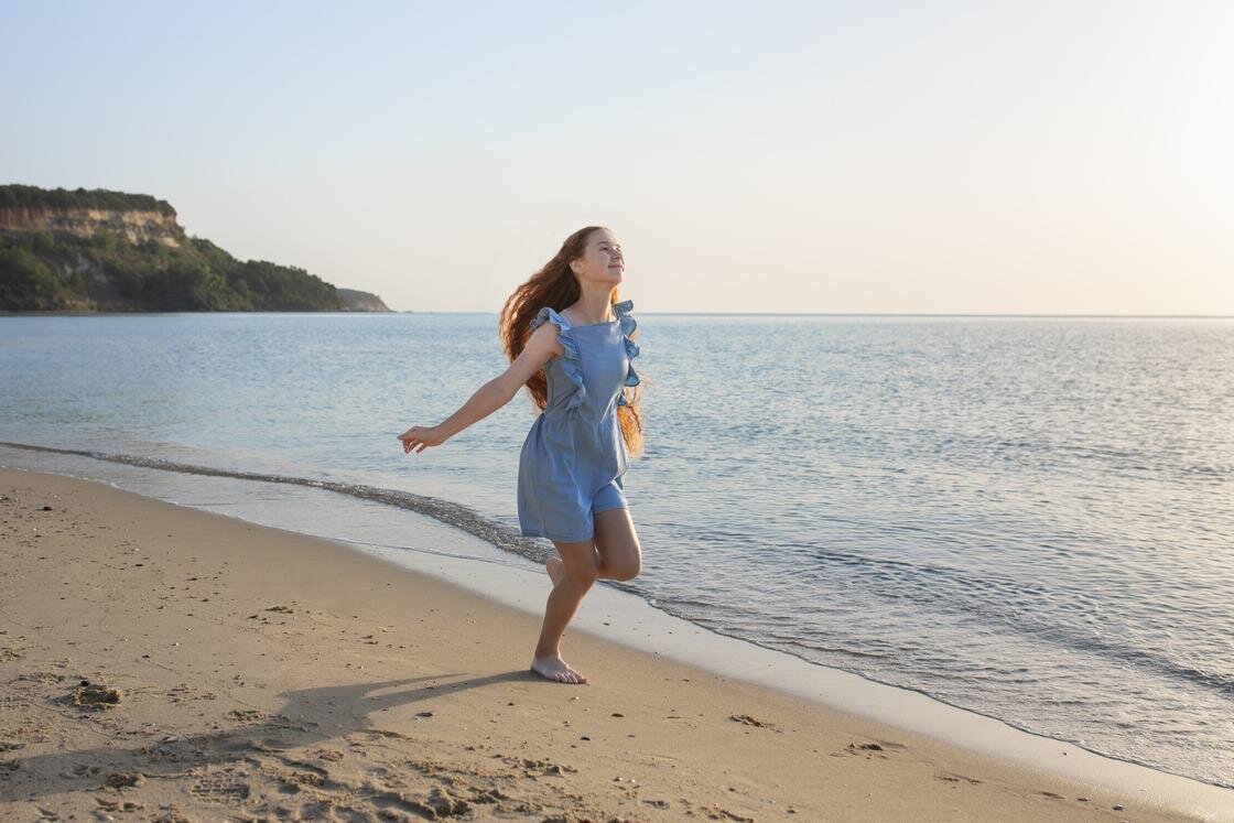    Девочка бежит по берегу моря:Freepik