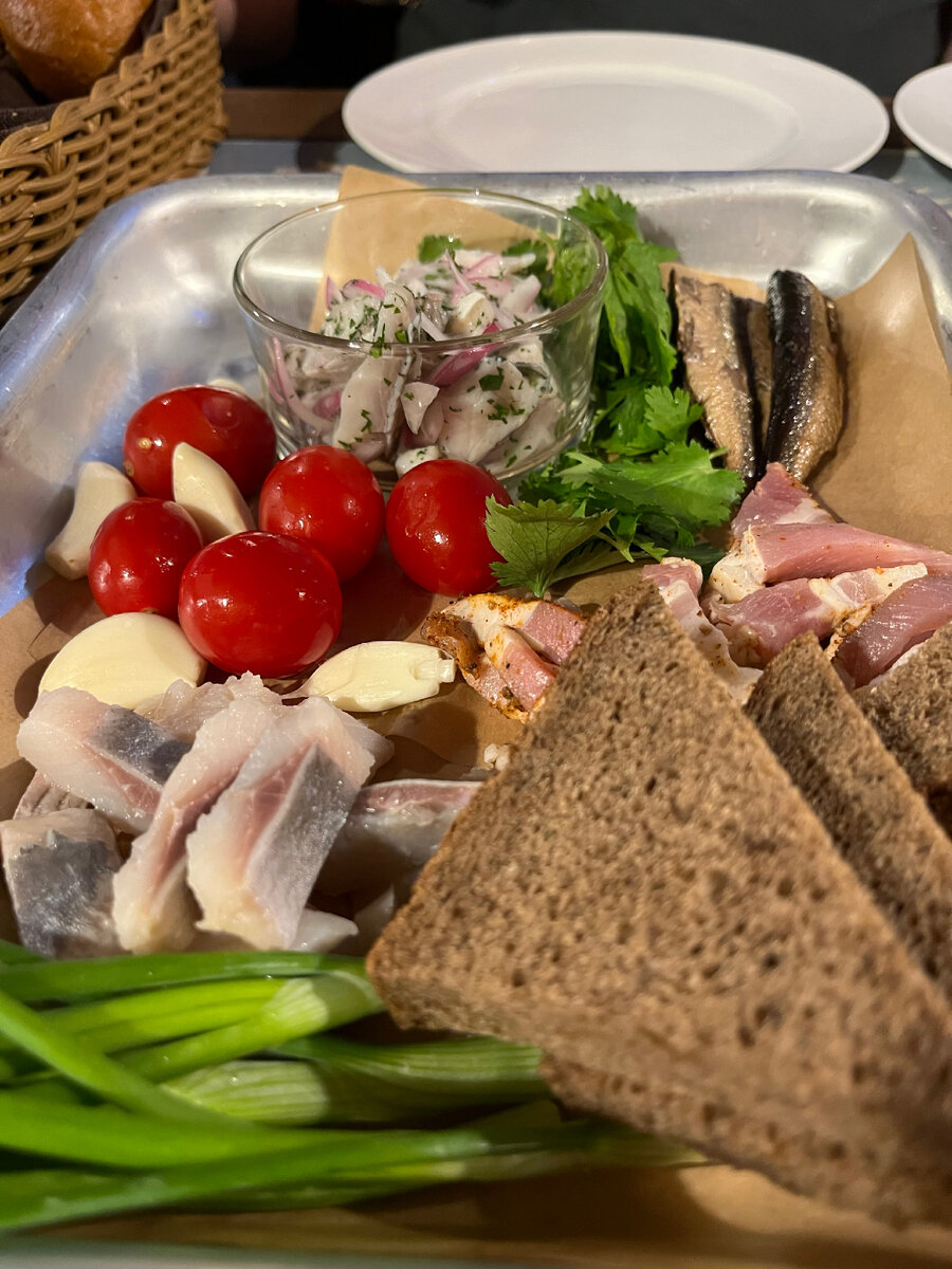 Состав: сельдь, картофель, сало, окорок, черных хлеб,  маринованный сом, корнишоны, буженина и соления.