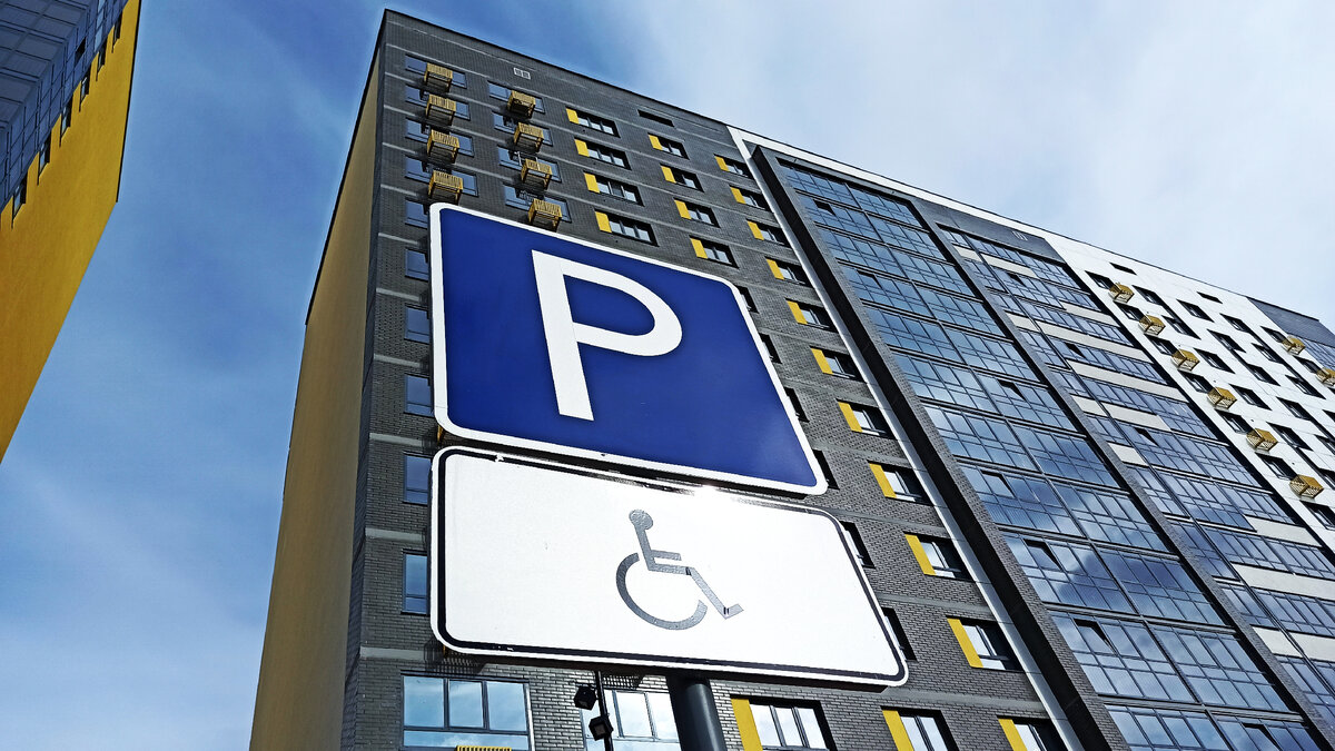 Знак парковки для инвалидов на фоне дома и голубого неба