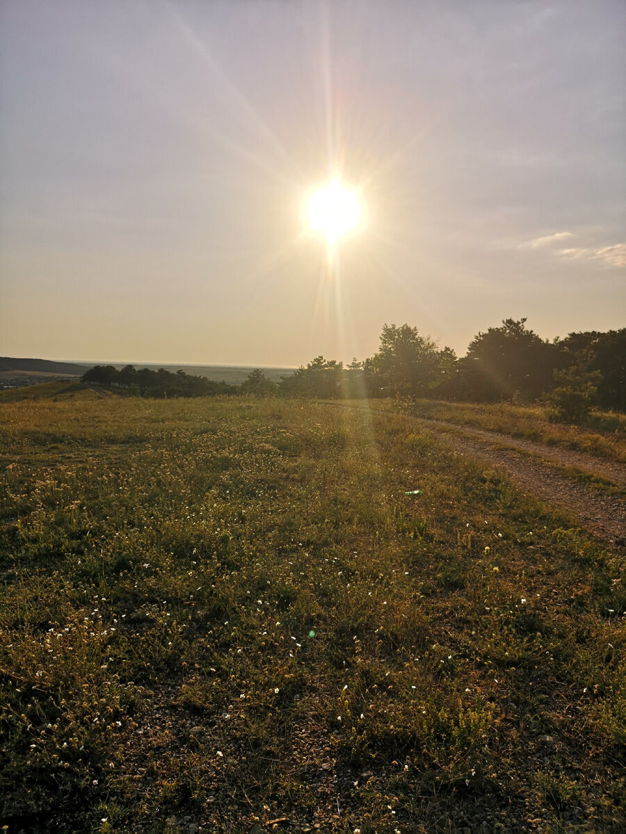 Прямо под лучами солнца блестит полоска моря.