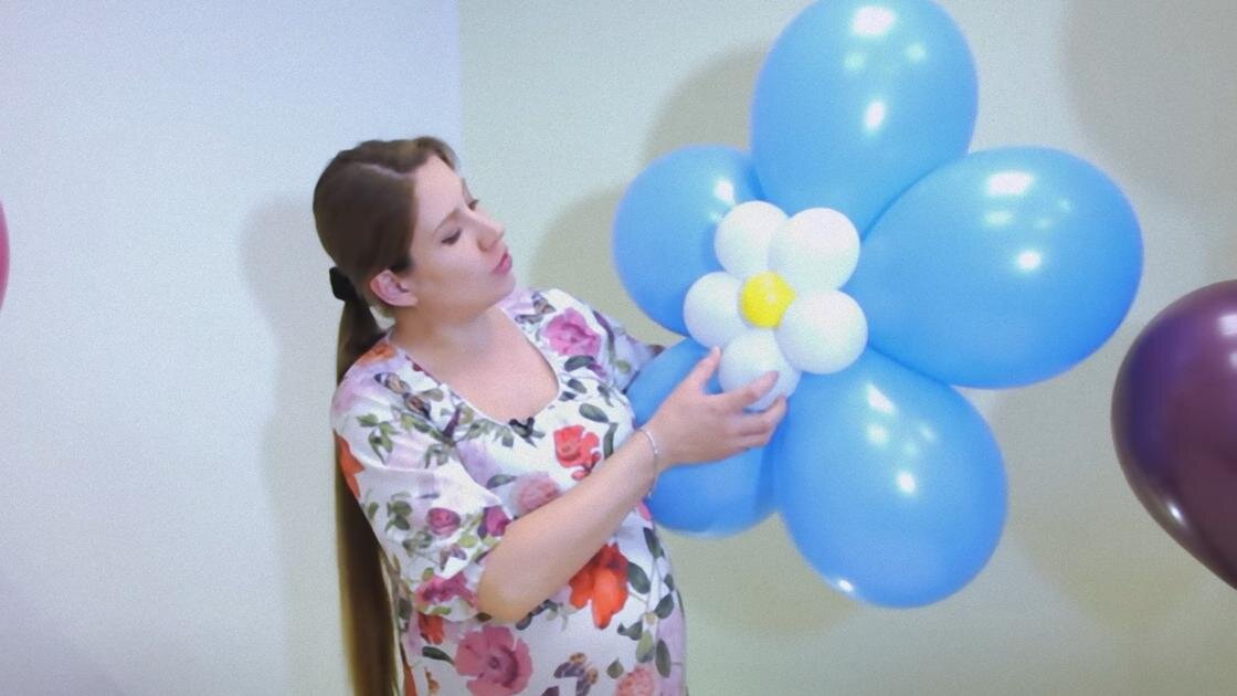    Женщина с длинным хвостиком держит в руке цветок из синих и белых шаров в виде ромашки:YouTube/Дон Баллон