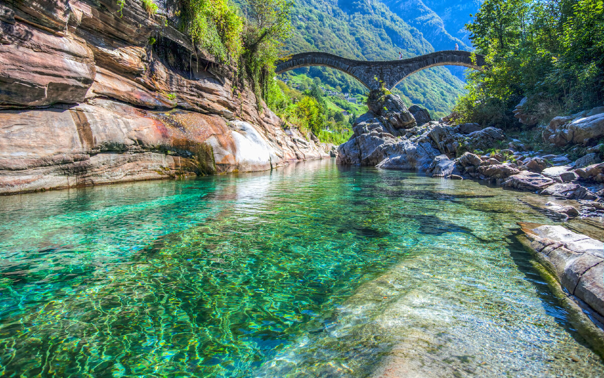 Кристальная вода Вердзаски.
Источник фото: https://img5.goodfon.com/original/5616x3521/b/53/valle-verzasca-lavertezzo-switzerland-locarno-most-reka-shve.jpg