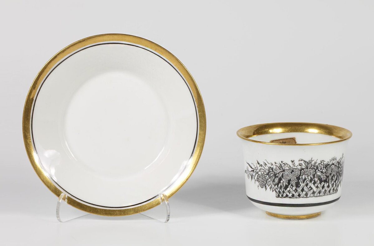 Чашка с блюдцем. 1921. Автор композиции Чехонин С.В., исполнитель Рукавишникова В.Ф. Роспись надглазурная монохромная, позолота. Размеры: 6,8*11,2*9,3 см. (чашка), и 2,8*14,5 см. (блюдце). Собрание Эрмитажа. Предмет поступил в 2002-м году. Передан в составе коллекции Музея Фарфорового завода. Инв. номер Мз-С-3235. Изображение взято из каталога Эрмитажа.