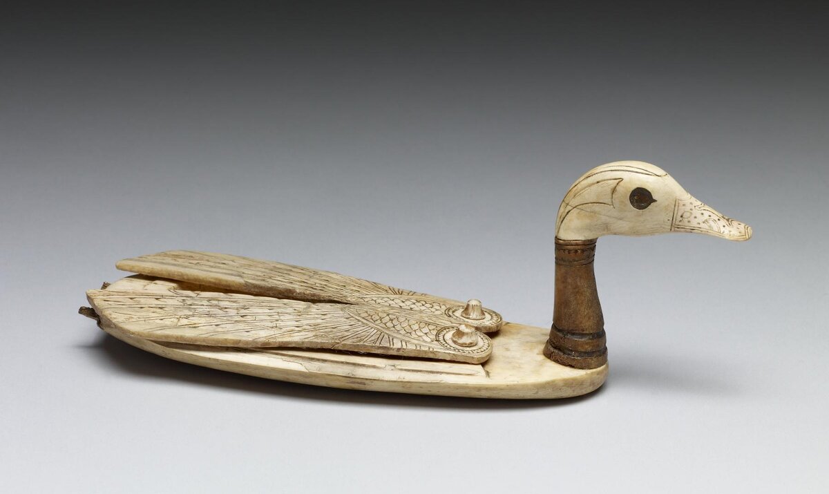 Коробочка для косметики, напоминающая знаменитую ложечку в виде девушки с лотосом.1550–1196 гг. до н. э. (Новое царство), слоновая кость. 7 x 6,6 x 20,5 см. Крылья этого очаровательного косметического контейнера поворачиваются наружу, открывая отсек для хранения. Глаза когда-то были инкрустированы. Утка-шилохвост - один из самых распространенных видов водоплавающих птиц в Египте и был популярным декоративным мотивом.