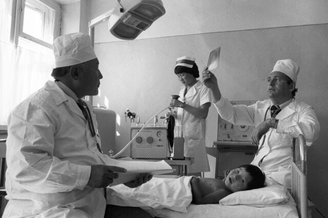    Руководитель группы советских детских врачей в МНР, доктор медицинских наук Леонид Рошаль (справа) осматривает пациента. Детская городская больница в Улан-Баторе. 1980 г. Фото:  РИА Новости/ Сергей Субботин