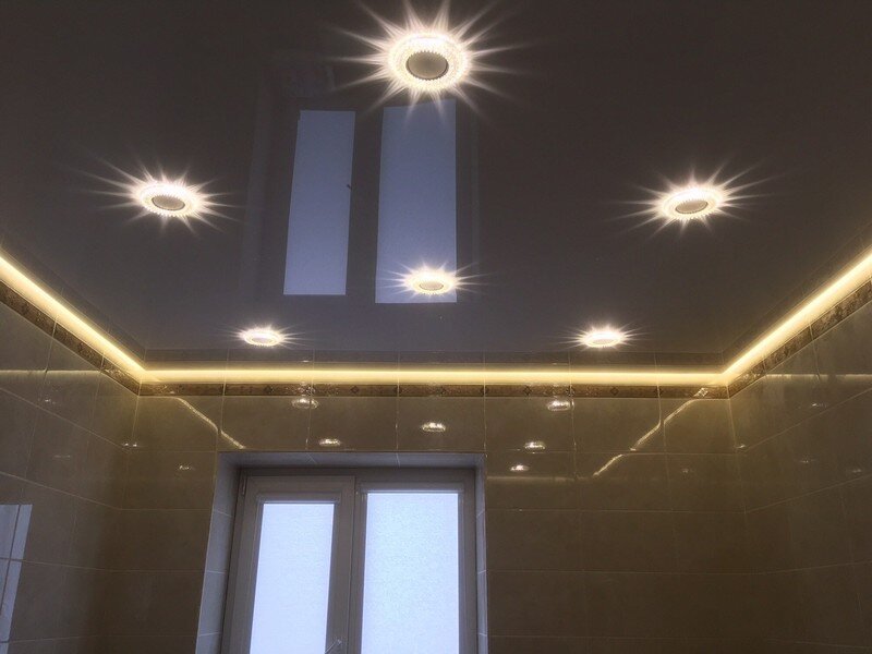 Белый лаковый парящий натяжной потолок с бежевой глянцевой керамической плиткой в ванной комнате.