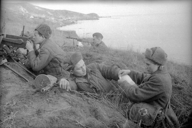 Санинструктор 369-го отдельного батальона морской пехоты Дунайской военной флотилии главный старшина Екатерина Илларионовна Михайлова (Дёмина, 1925 г.р.) перевязывает раненого во время боя в районе Керчи.Фото взято из открытых источников.