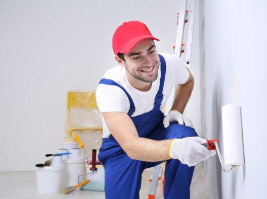    Young worker painting wall in room