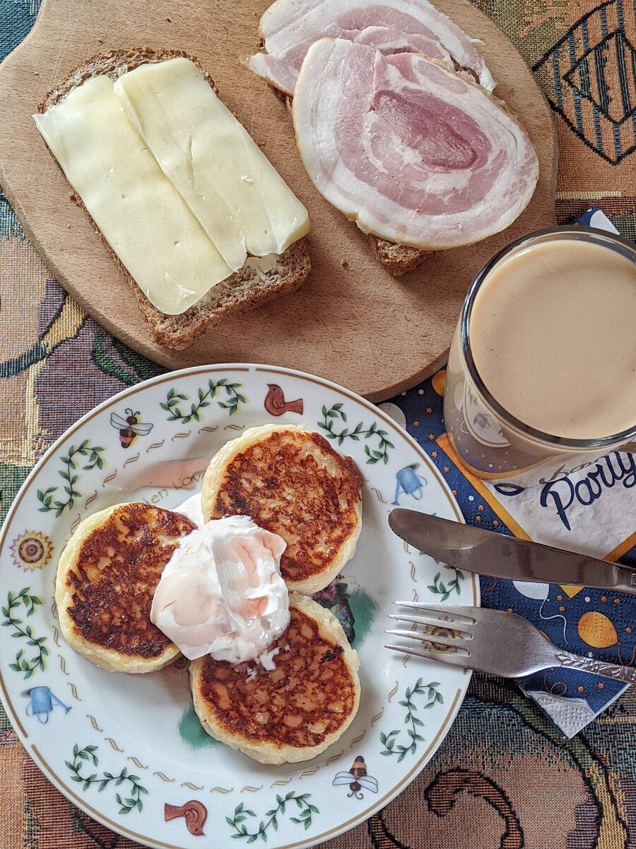 Сырники со сметаной и клубничный сироп, цельнозерновой хлеб, масло, сыр, рулет, кофе с молоком