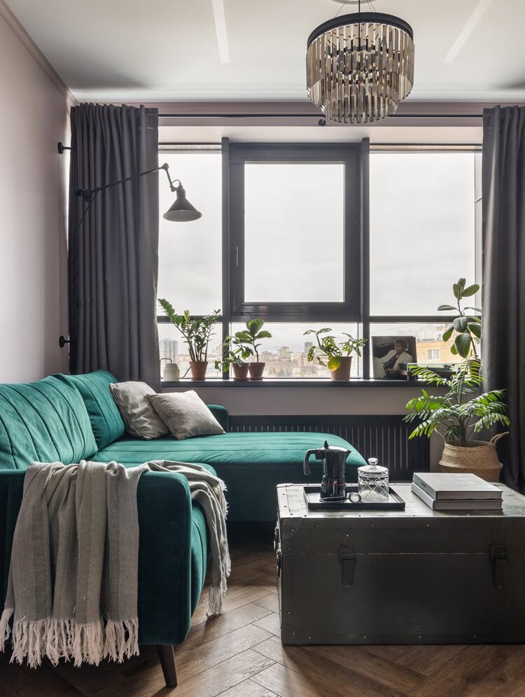 Гостиная в квартире по дизайну Надежды Токаревой в Уфе. Диван, divan.ru. Люстра, Vitaluce. Бра над диваном, La Redoute. В качестве журнального столика используется армейский сундук. На стенах краска, Derufa. На полу кварц-виниловая плитка, Alpinext.