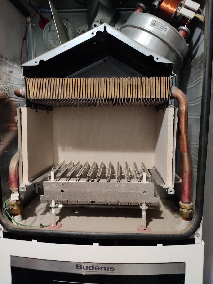 Открытая камера сгорания котла Buderus U72. До чистки. Видны вентилятор, теплообменник, горелка, электроды розжига и ионизации. На задней стенке притаился прессотат. (фото автора)