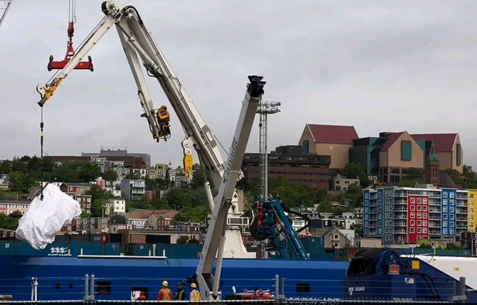 Погрузка обломков батискафа с корабля в грузовики в порту Ньюфаундленда